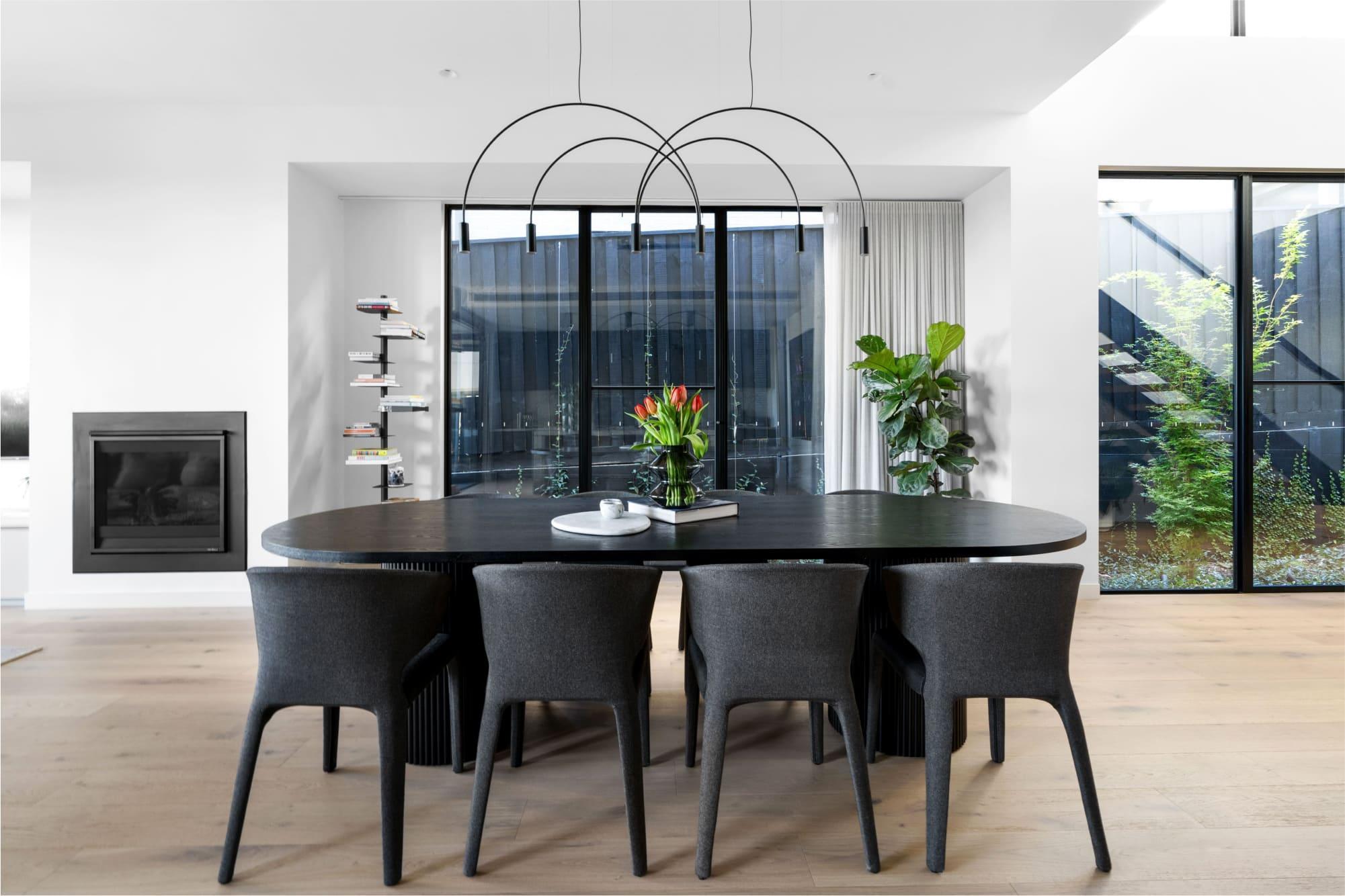 A modern dining space with eye catching pendant and floor to cieling windows