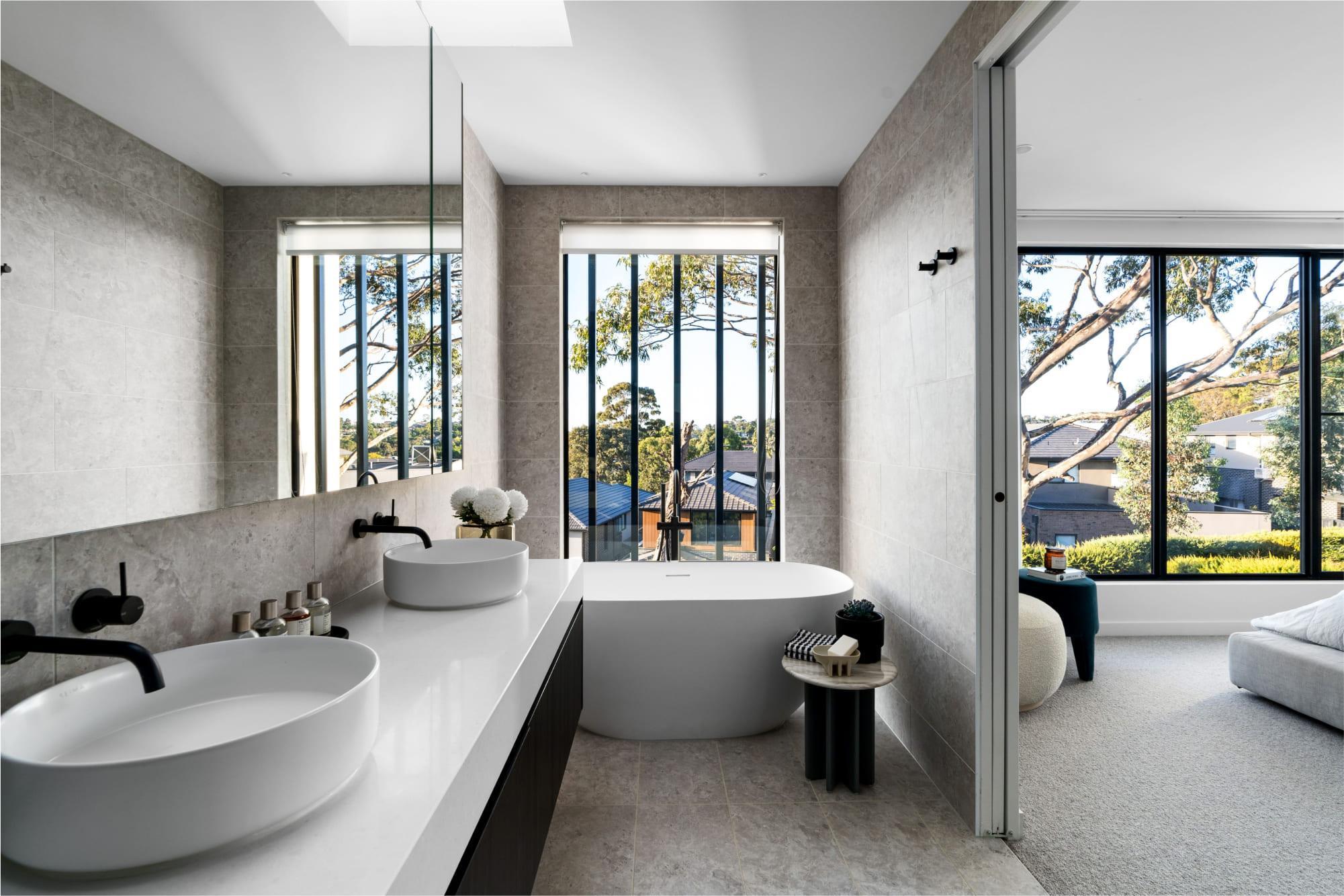 A luxurious ensuite with floor to ceiling stone tiles with a large window 