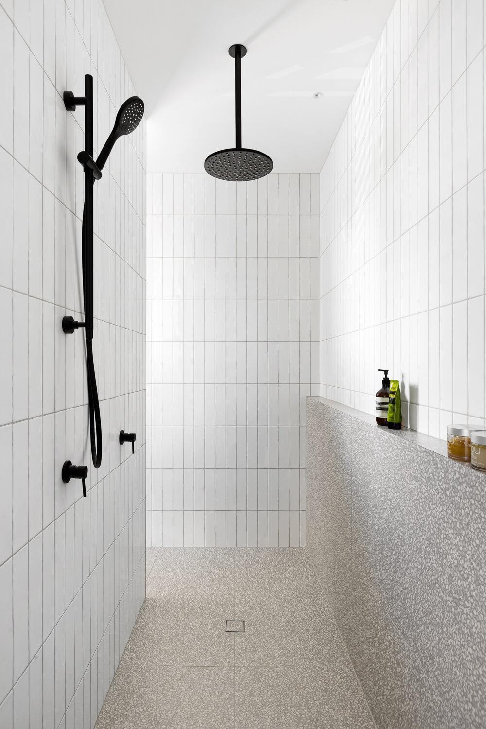 Large walk in shower with white tiles and grey stone