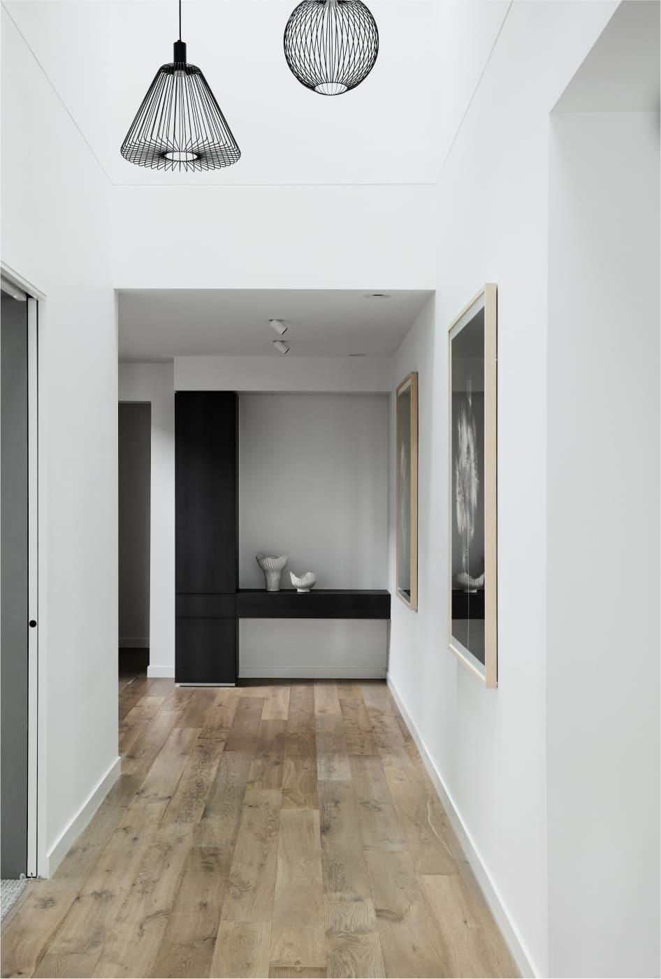 Expansive hallway with timber floors and feature void pendants