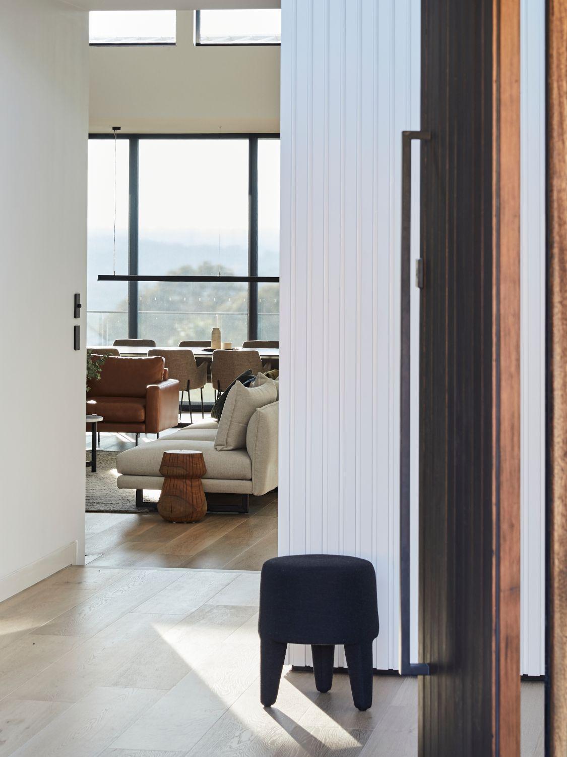 Warm Timber Pivot Entry Door Contrasts Against Light Material Selection