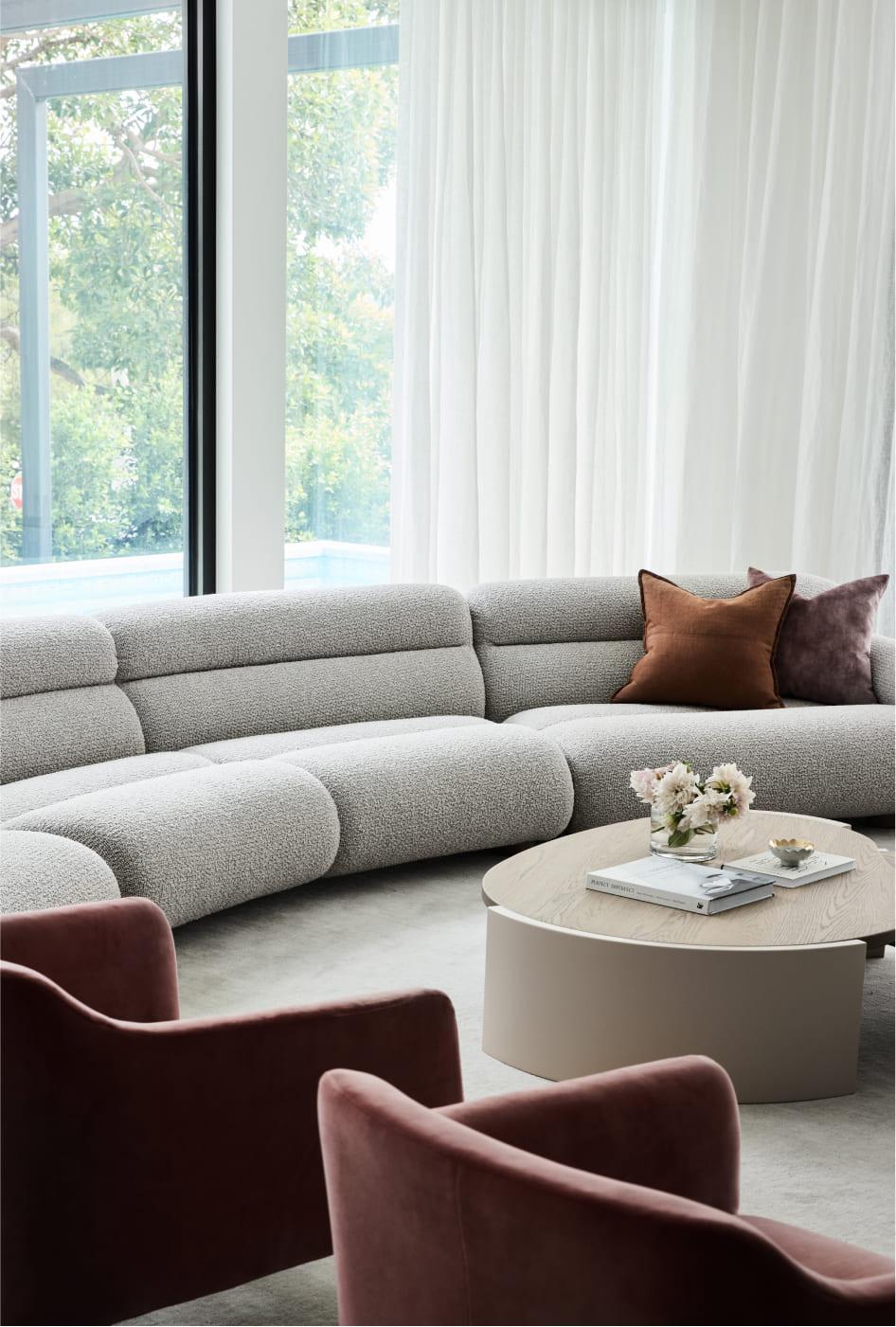 A curved couch in the living area with floor to ceiling windows