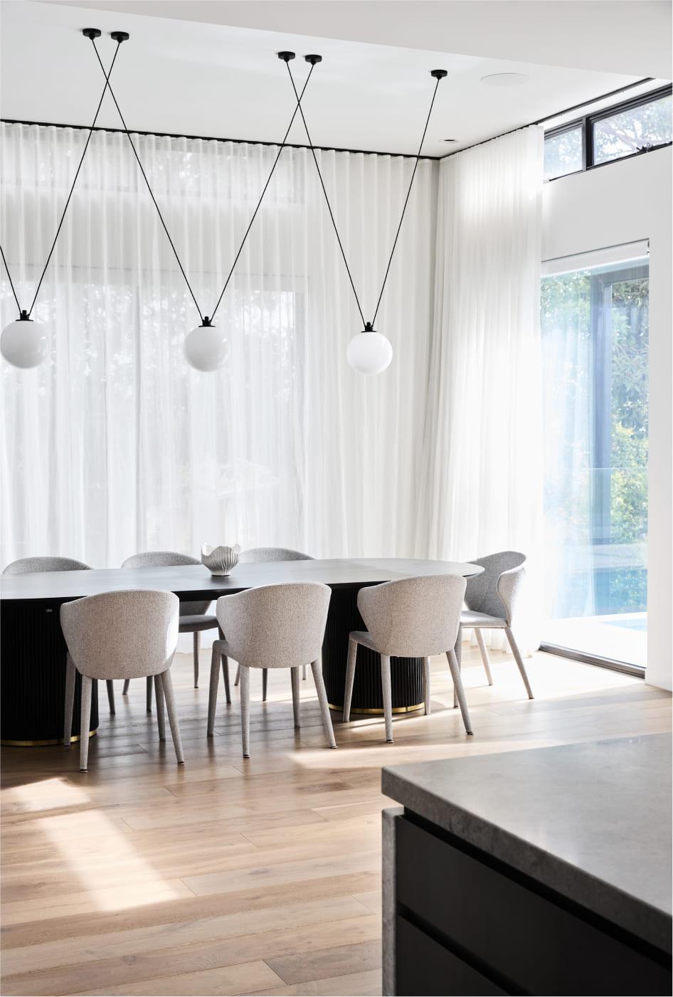 A large dining a space with feature pendants, floor to ceiling windows and sheers