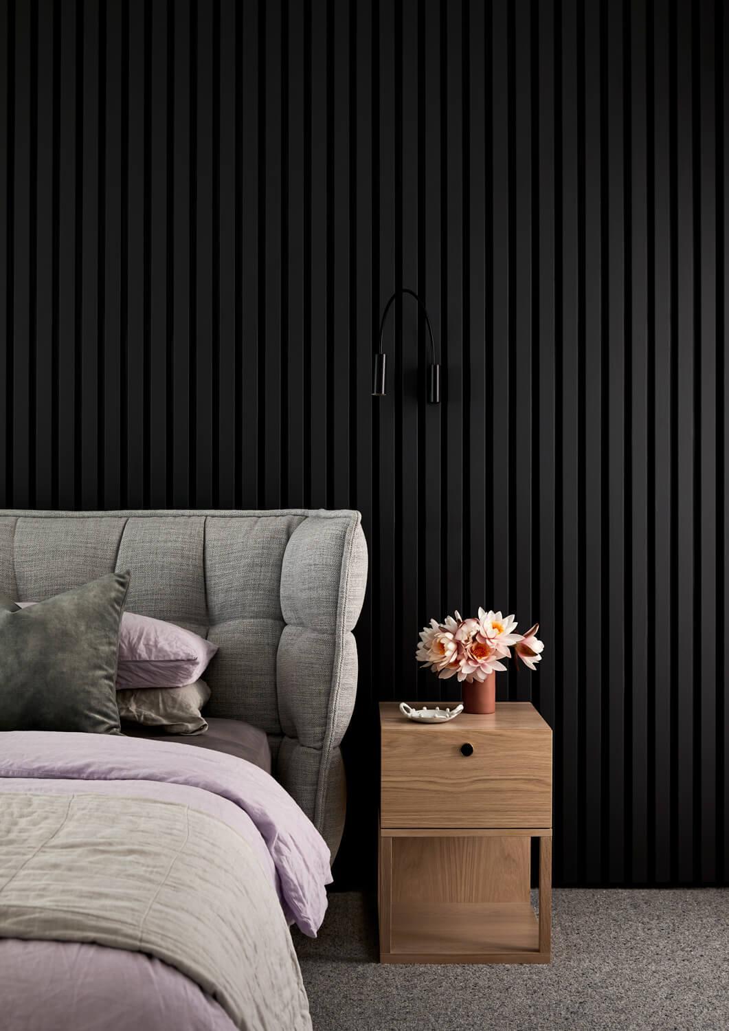 Warm Bedroom Furniture Contrasts Against Black Wall Cladding