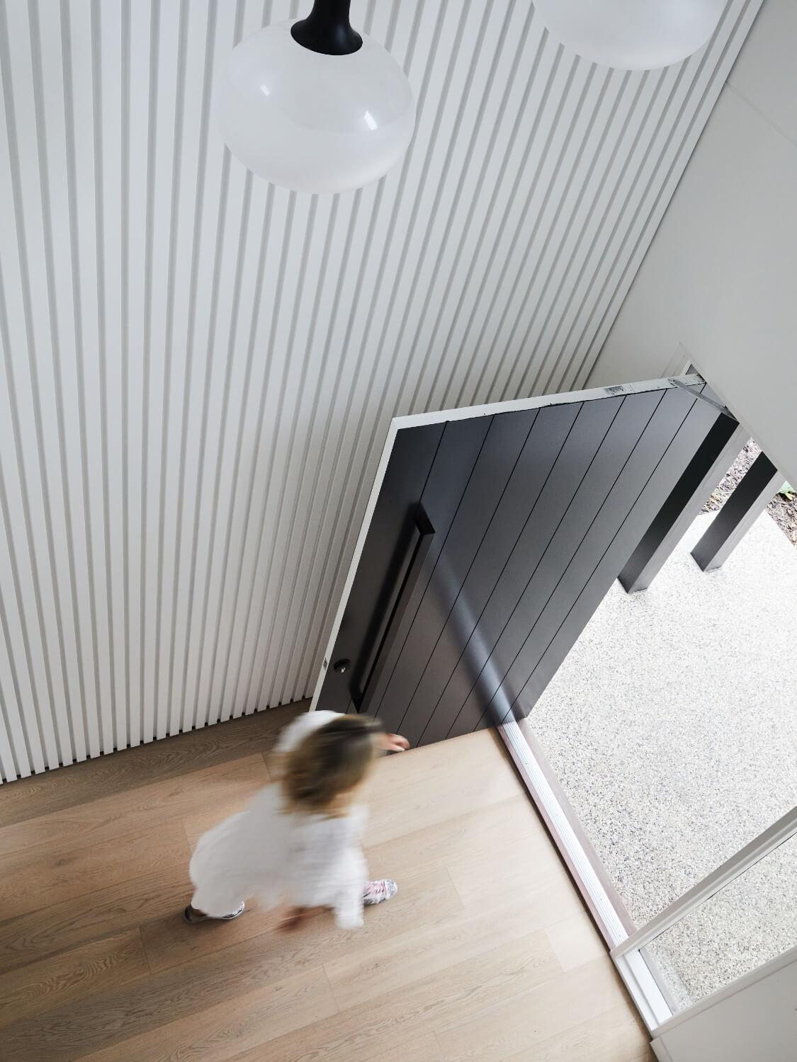 White And Black Cladding On Entryway Wall And Pivot Door