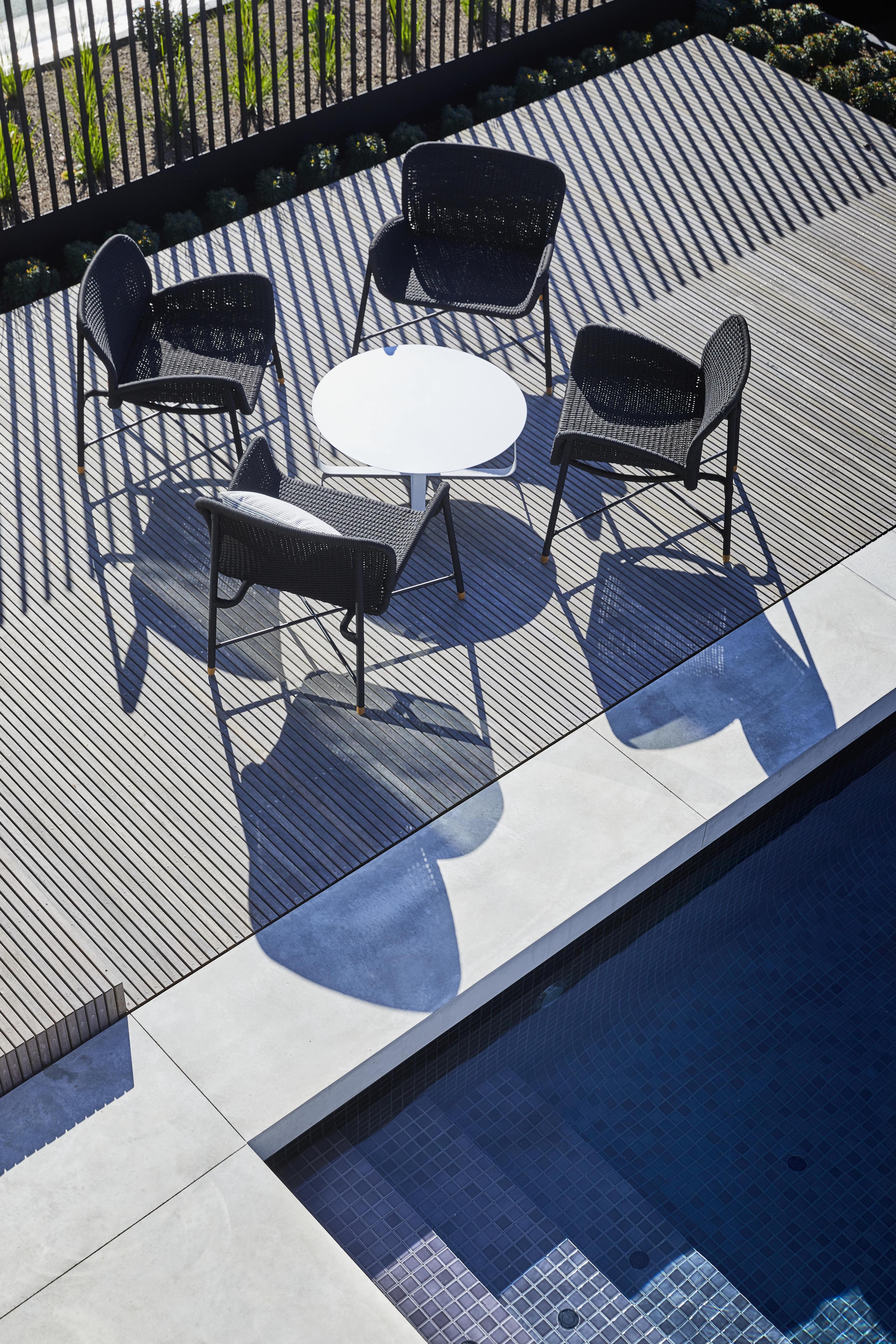 An outdoor table and chair on a deck beside a pool