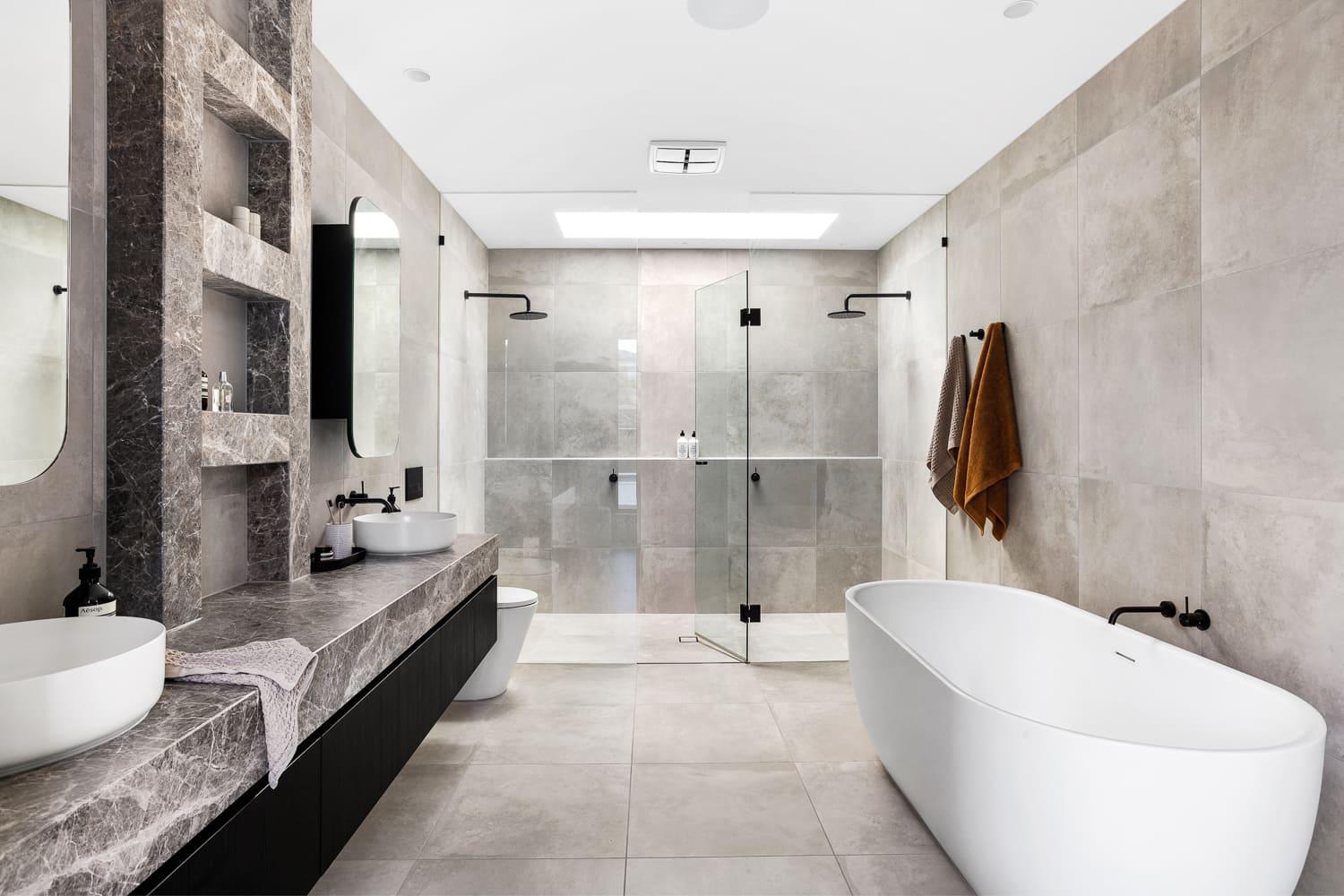 a modern bathroom with a large tub, grey tiles and grey stone marble bench