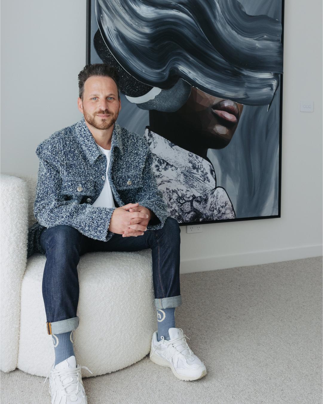 Brent Rosenberg sitting in front of large scale painting, 'Heaven at night' 