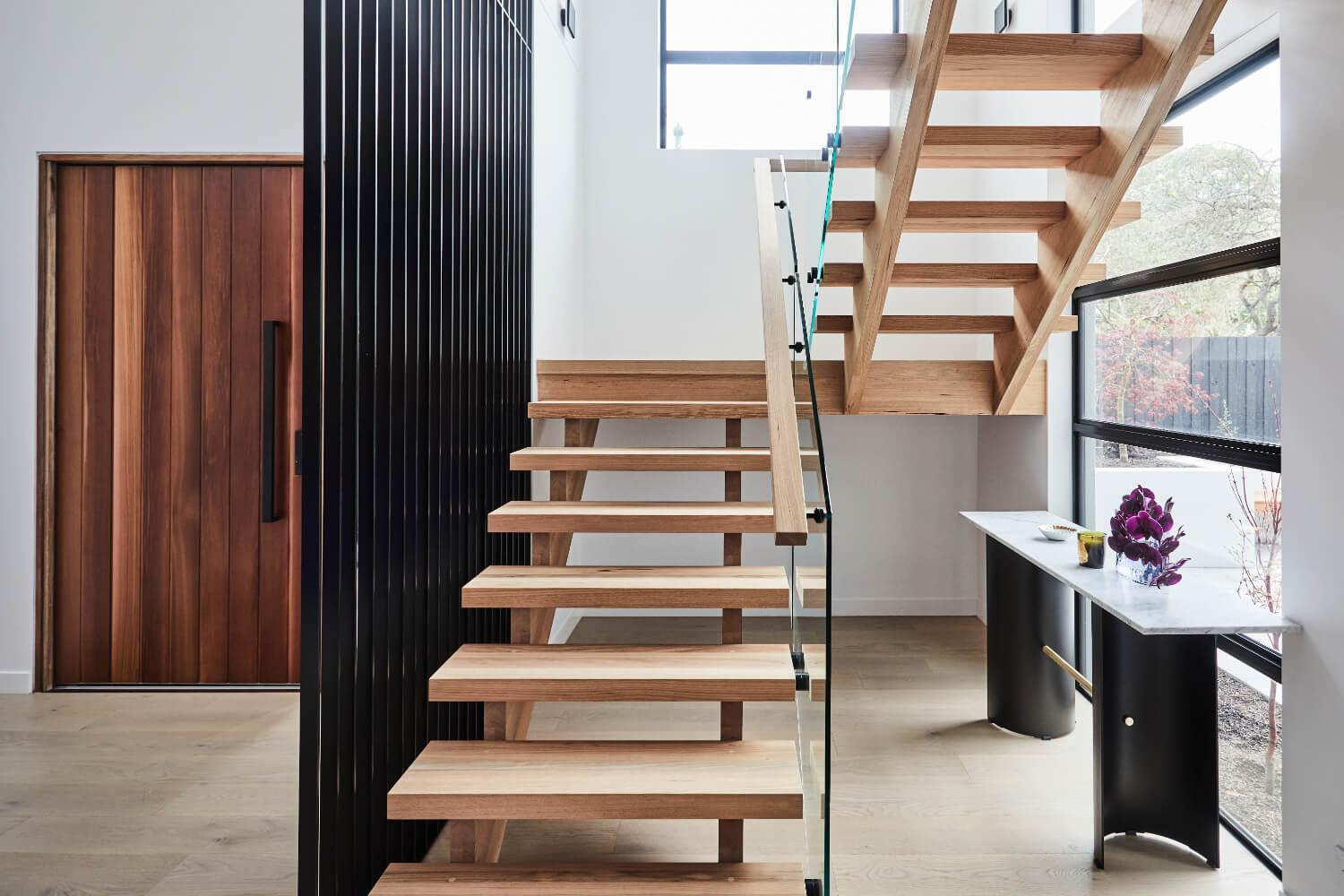 Open Natural Timber Staircase With Glass Balustrade And Black Metal Screen