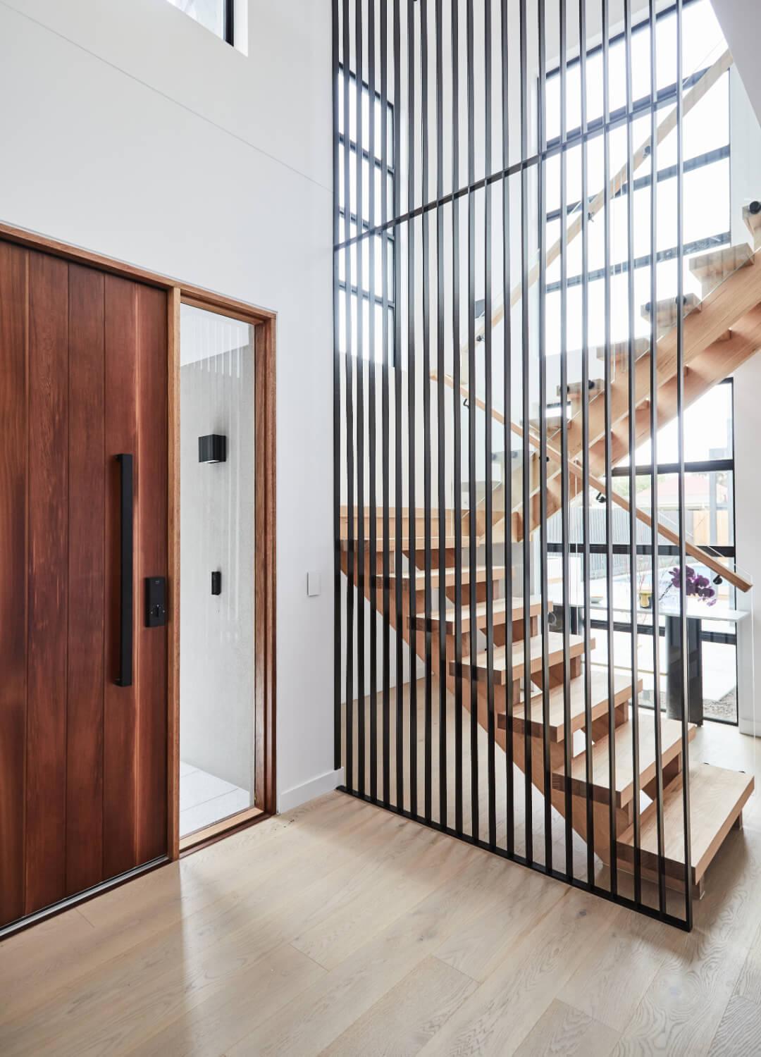 Black Metal Screen Obscures Freestanding Timber Staircase